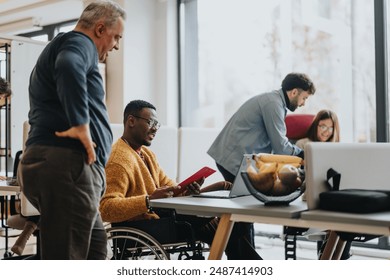 An inclusive modern office environment with a diverse team collaborating. A person in a wheelchair actively engages with colleagues. - Powered by Shutterstock