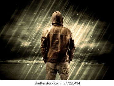 An Incognito Hooded Stalker Standing In The Rain With His Back In Front Of Dark Scary Landscape Concept