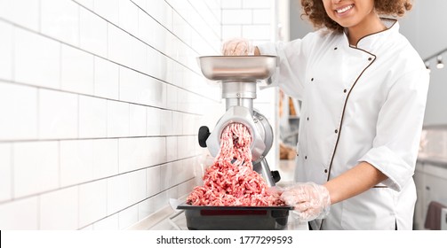 Incognito smiling woman with curly hair putting small pieces in meat grinder and grinds them into mincemeat. Crop of female working in butchery, preparing meat for selling in shop. - Powered by Shutterstock