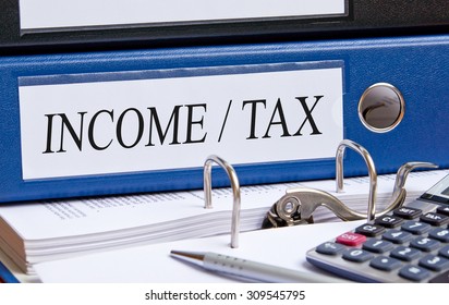 Income and Tax - blue binder on desk in the office - Shutterstock ID 309545795