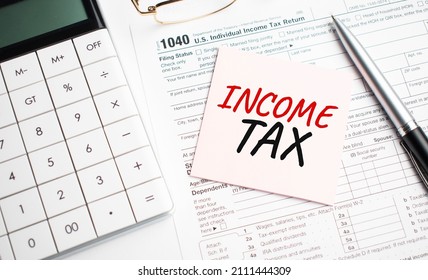 INCOME TAX with pen, calculator, glass and sticker. Tax report sign