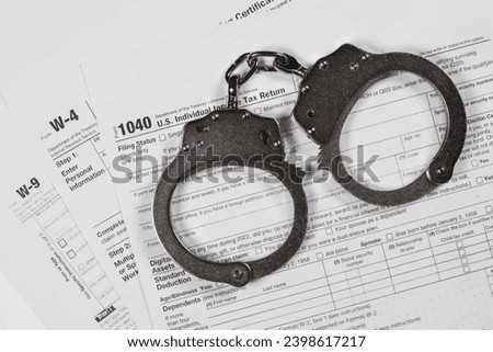 Income tax return documents and handcuffs. Tax evasion, crime and fraud concept