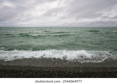 An incoming wave on the Black Sea and a pebble beach on the Sochi coast on a summer day with clouds, Sochi, Krasnodar Territory, Russia - Powered by Shutterstock