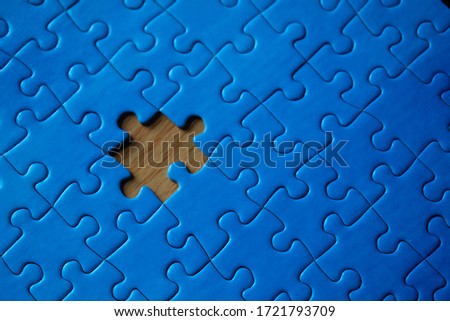 Incomplete blue piece puzzle with a missing piece over a wooden table