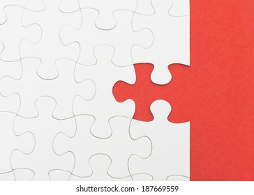 Incomplete white puzzle with red color background with copyspace.