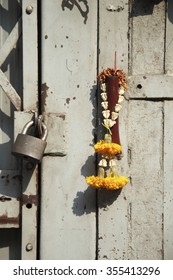 Incongruous glimpse of faith: old metal door, lock, and flower garland and burned incense stick