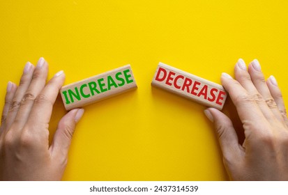 Increase or Decrease symbol. Concept word Increase or Decrease on wooden blocks. Businessman hand. Beautiful yellow background. Business and Increase or Decrease concept. Copy space