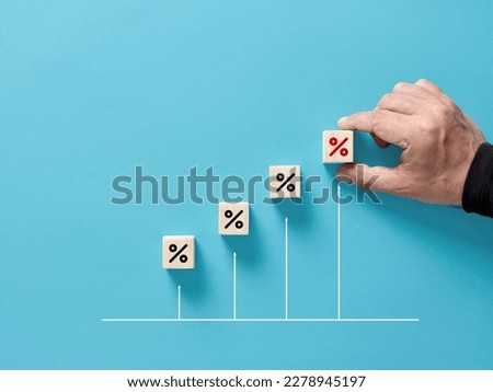 Increasing percentage rate concept. Business and finance. Market share. Interest, loan or inflation rate. Male hand arranges the wooden cubes with the percent rates on an ascending graph.