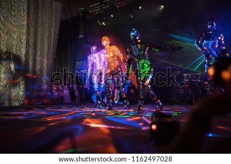an incredible beauty of the performance of artists and dancers on stage, a fireshow with LED suits and lasers reflecting on a lot of mirror details in clothes, iridescent with all the colors
