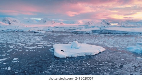 Incredible bright sunset over Antarctica landscape. Ice, cold ocean, glaciers, snow-capped mountains, colorful cloudy sky. Breathtaking journey over frozen untouched nature. Aerial drone flight - Powered by Shutterstock