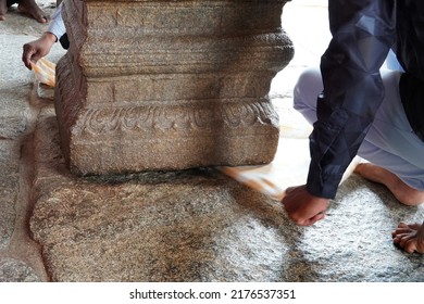 The incredible hanging pillar, Veerabhadra Shiva temple, Lepakshi, Andhra. Visitors passing a towel underneath the pillar to test if there is a gap between the floor and the pillar.           