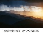 An incredible scene of a heavy downpour illuminated by the rays of the sun at sunset. A unique natural phenomenon. Location place Carpathian mountains, Ukraine, Europe. Discovery the beauty of earth.