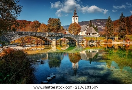 Incredible Sunny nature landscape with fabulous mountain lake in Slovenia. beautiful lake Bohinj with perfect sky at summer. view on calm lake with azure water, church and stone bridge on background.