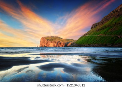 Incredible sunset in low tide time on Atlantic ocean coast near village Tjornuvik. Famous rock formations Risin and Kellingin Eidiskollur on background. Faroe Islands, Denmark. Landscape photography - Powered by Shutterstock