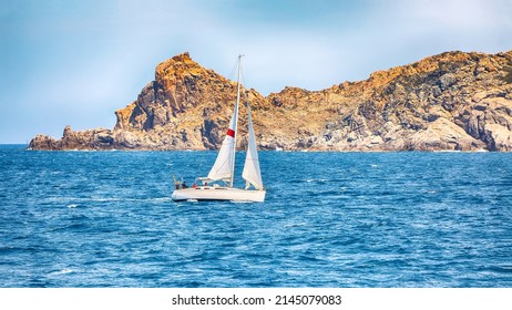 Incredible view of sailboat sailing near the cliffs of  Santa Teresa Gallura. Popular travel destination of Mediterranean sea. Location: Santa Teresa Gallura, Province of Sassari, Sardinia, Italy