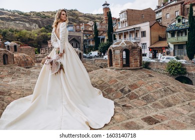 Incredibly Charming Bride Poses For A Photo In A Sophisticated Wedding Dress On The Background Of Old Georgian City Tbilisi