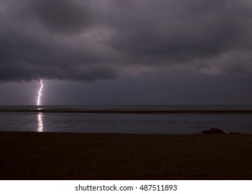 Incredibly sharp lightning with branches hitting the ocean with reflected light