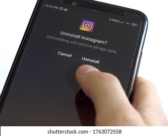 Indaiatuba, SP / Brazil - June 24 2020: User holding a smartphone removing uninstalling the social media app Instagram