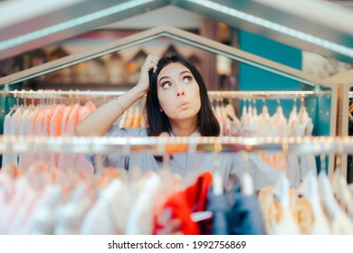 Indecisive Female Customer Standing Among Clothing Racks. Conscious consumer thinking before buying something in fashion shop
