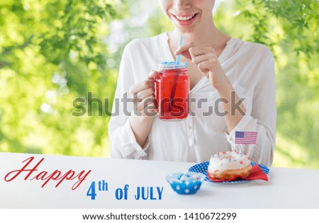 independence day, celebration and holidays concept - close up of happy woman with glazed sweet donut drinking juice from glass mason jar or mug at 4th july party over green natural background