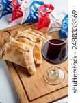 Independence Day feast featuring Chilean baked meat empanadas and red wine on a wooden board. Tradition and taste