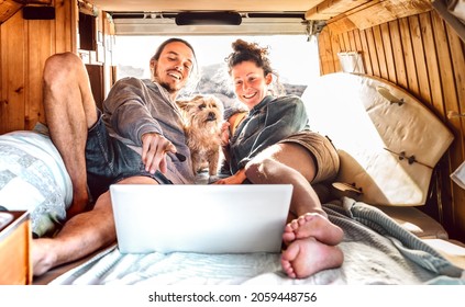 Independent couple with cute dog using laptop on retro mini van transport - Travel life inspiration concept with indie man and woman on minivan adventure trip watching pc on relax moment - Warm filter