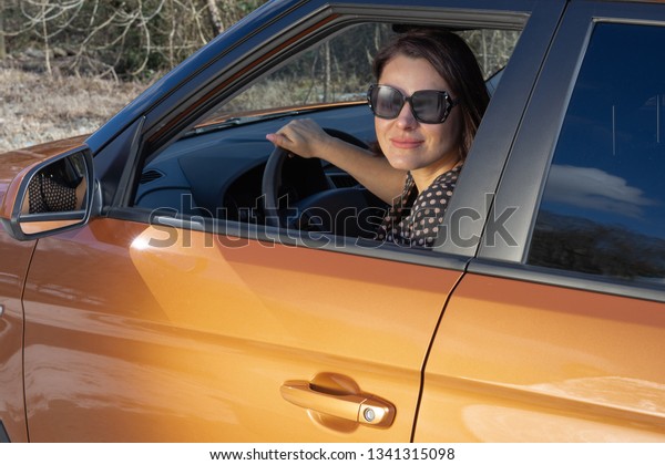 A\
independent woman sitting behind the wheel of her suv smiling and\
looking at camera. The concept of women\'s\
equality