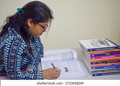 India 2020 : Girl With Eye Glasses Studying During Exam Time. Books Of Various Subjects Are Kept On The Table. She Is Holding A Pencil And Highlighting The Important Topics