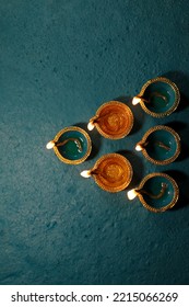India, 4 October, 2022 : Happy Diwali Festival of Lights teal color background with teal and golden color traditional clay oil lamps Diya lit during Dipavali celebration, wallpaper, Image, concept. - Shutterstock ID 2215066269