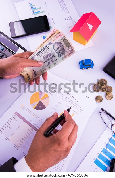 India and accounting concept showing\
accountant working on Income tax forms or on budget planning with\
currency notes, calculator and house/car 3d\
Models