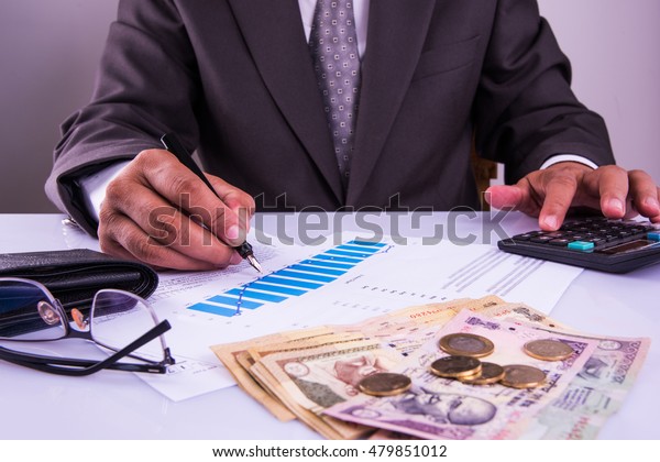 India and accounting concept showing\
accountant working on Income tax forms or on budget planning with\
currency notes, calculator and house/car 3d\
Models