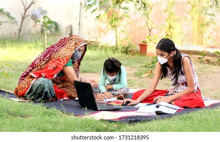 India Defeating Corona Virus. Indian Rural Mother Teaching Her Daughters Online On Laptop Using Internet. Use Of Technology In Indian Villages. Mother And Daughter Wearing Masks To Keep Away Covid-19.