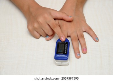 India, Hand Of Asian Child Girl With An Attached Pulse Oximeter On Fingertip Measuring Heart Rate,checking Oxygen Saturation Level In The Blood,diagnosis Of Coronavirus Or COVID-19 At Home Health Care