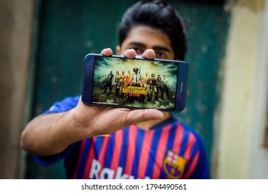 INDIA, KOLKATA - August 12, 2020: Boy showing PUBG game on Android mobile phone on green background