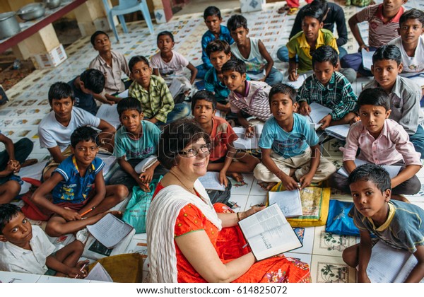 India - March 11, 2015: Missionary woman\
teach poor rural indian children in the\
school\
