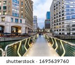 India place and Cabot square united by a footpath bridge illuminated at dusk near Canary Wharf in London. 