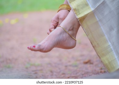 Indian anklet feet of a beautiful kerala girl , with treditional saree, couture of wearing gold and golden ankle, kerala style potrate with hand and red nail polish, queen of natural beauty 