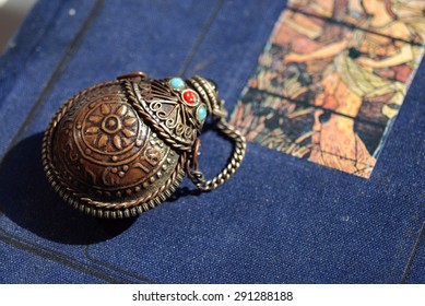 The indian antiquarian bottle for perfume with beautiful ornament on it. The background is a blue texture. The focus is on the object. The composition is comfortable for designers' requirements.