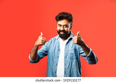 Indian asian bearded young man celebrating success against red background