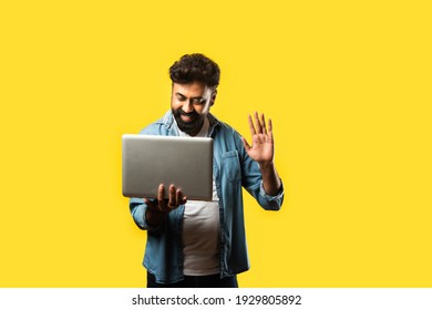 Indian Asian Bearded Young Man In Casual Cloths Using Laptop While Standing Against Yellow Background