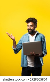 Indian Asian Bearded Young Man In Casual Cloths Using Laptop While Standing Against Yellow Background