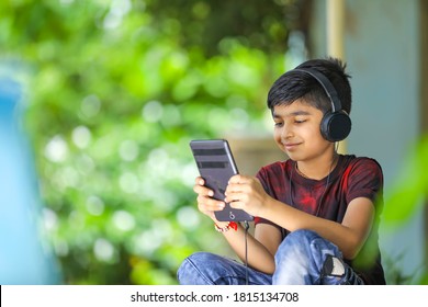 Indian / Asian Boy Listening Music Or Learning On Mobile Phone