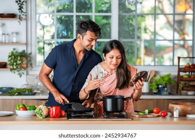 Indian asian couple preparing food at the stove with partner  in kitchen - Powered by Shutterstock