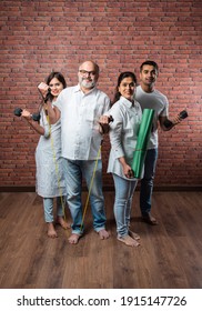 Indian Asian Family Exercising At Home. Senior Parents With Young Kids Doing Yoga, Lifting Weight, Using Theraband In Living Room Interior. Indoor Workout Concept