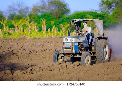 Indian / Asian farmer with tractor preparing land for sowing with cultivator, An Indian farming scene