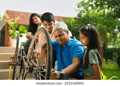 Indian Asian father repairing his child's bicycle on the house porch, with his son and daughter watching eagerly, while the wife looks on with a smile, capturing a happy family moment - Powered by Shutterstock