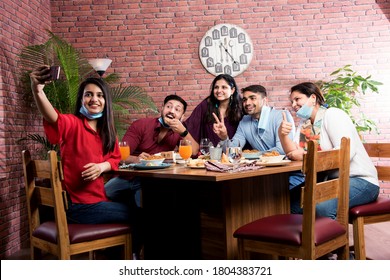 Indian Asian Friends Eating In Restaurant Dining Concept Wearing Protective Face Mask After Corona Pandemic