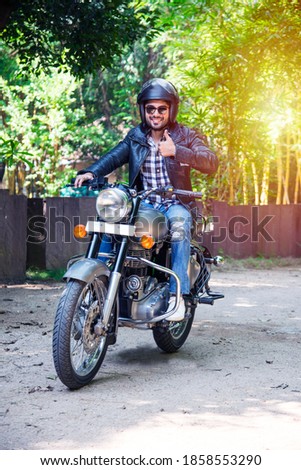 Indian asian man riding modern scrambler motorbike on the forest road. having fun driving the empty road on a motorcycle tour journey.