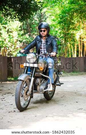Indian asian man riding modern scrambler motorbike on the forest road. having fun driving the empty road on a motorcycle tour journey.