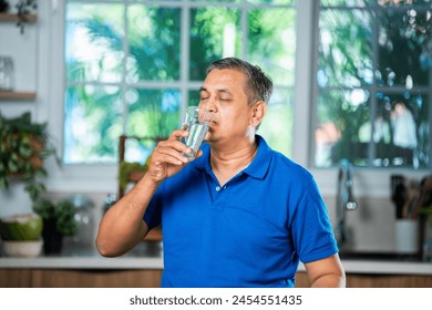 Indian asian mid age handsome man drinking plain water in a glass at home - Powered by Shutterstock